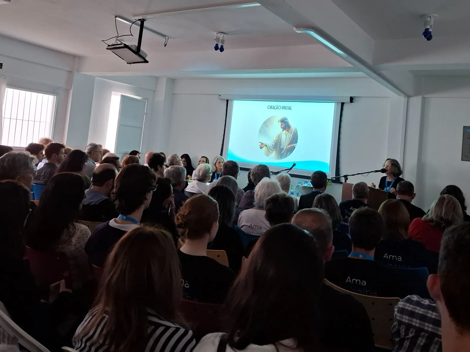Salão do CECAL durante a palestra: fileiras de cadeiras ocupadas, pessoas de costas olhando para a tela projetada à frente.